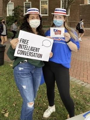 two people wearing patriotic hats holidng a sign saying Free intelligent conversation